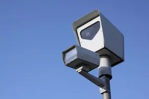 Traffic camera mounted on a pole against a clear blue sky.
