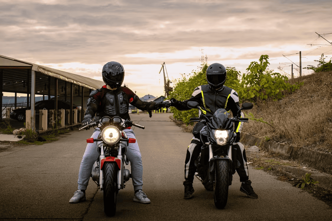 Two stationary mototrcyclists on their bikes wearing appropriate safety gear