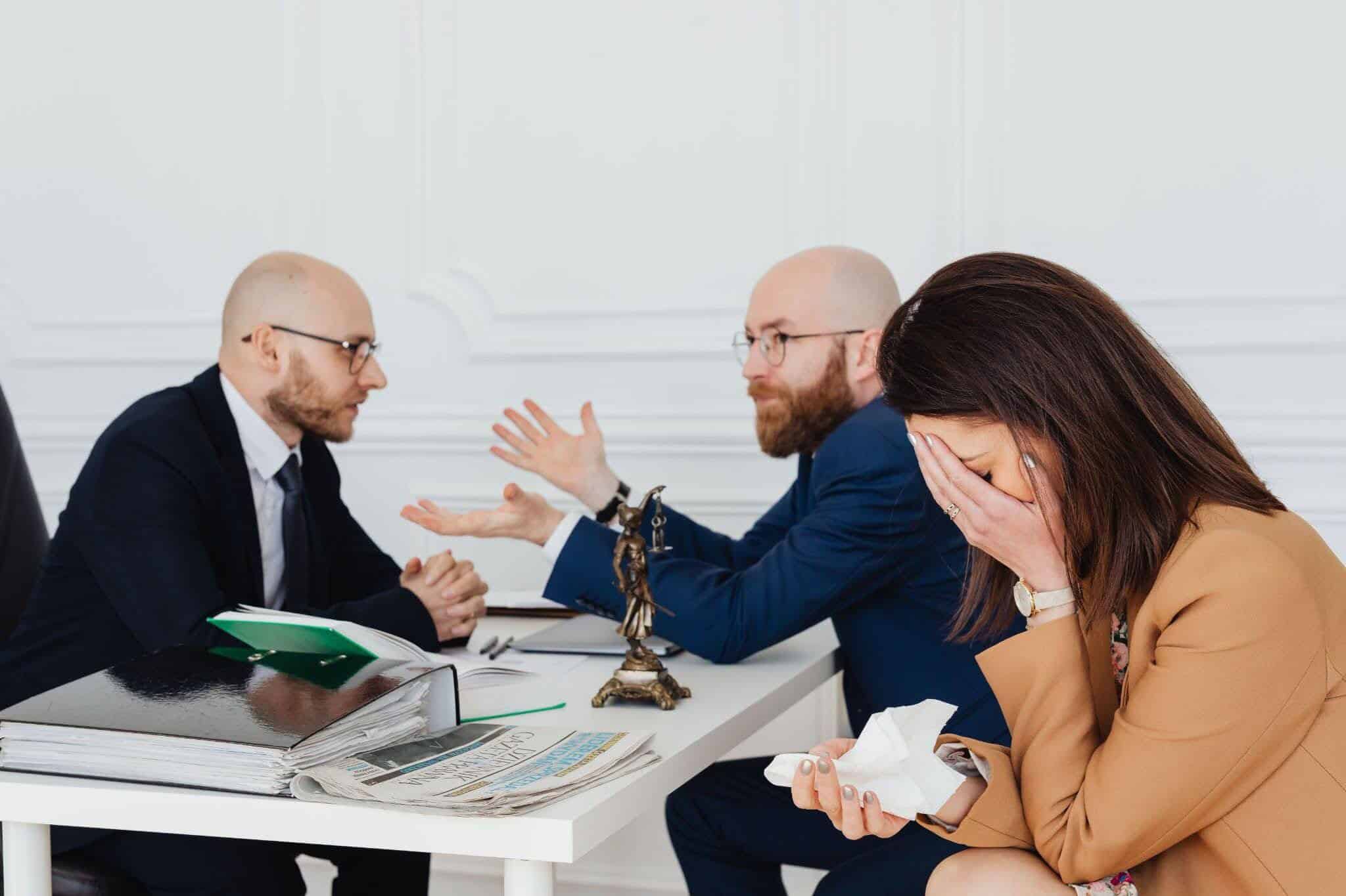 A grieving woman meets with attorneys in a law office.