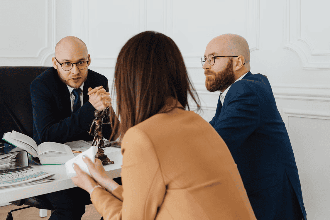 lawyer speaking with two people in office at desk