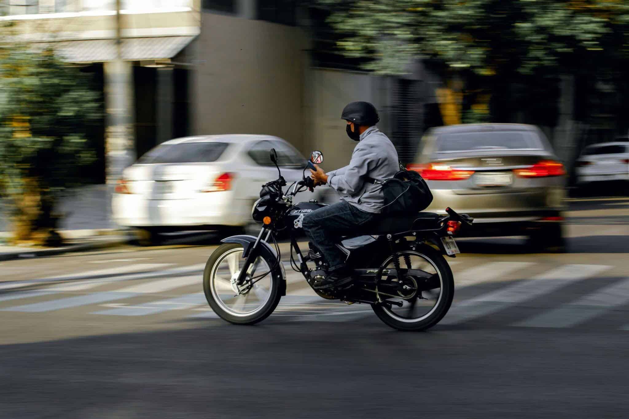 A helmeted motorcyclist navigates city traffic.