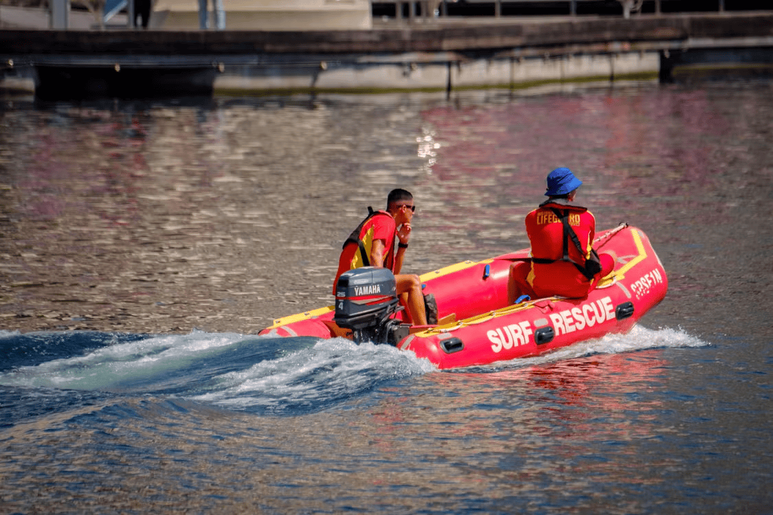 A surf rescue pontoon boat and two-person crew on the water