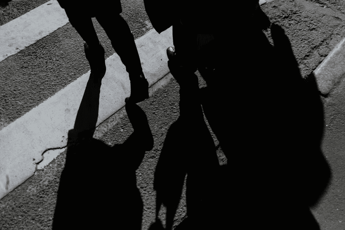shadows of two people crossing the street