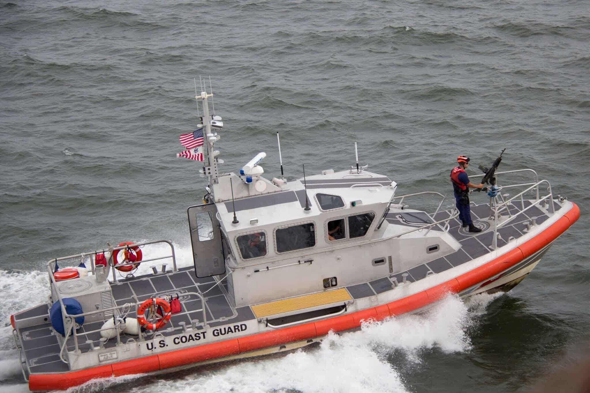 A U.S. Coast Guard response boat speeds across choppy water, American flag flying